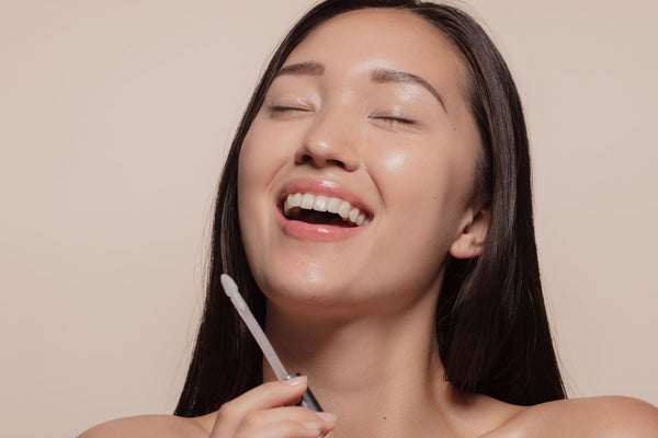 Woman applying a makeup product while looking happy.